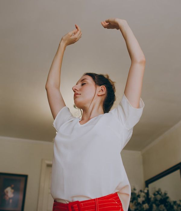 Woman stretching arms towards the sky in a bright living room
